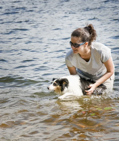 Jovem mulher brincando e seu cão pastor no lago — Fotografia de Stock