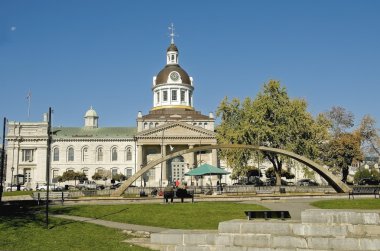 tourists sit on a bench in front of city Hall of Kingston and Confederation arch fountain, Ontario Canada clipart