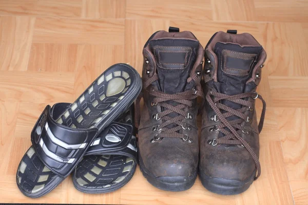 Chanclas y botas para hombre en suelo de madera —  Fotos de Stock