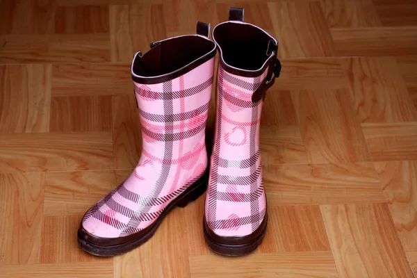 Růžový déšť boty na dřevěnou podlahu — Stock fotografie