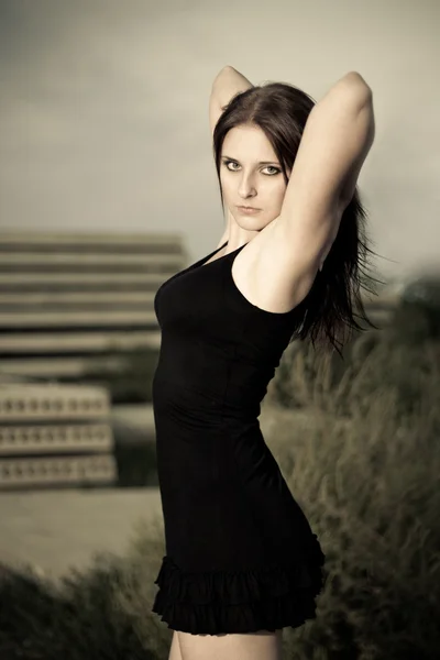 Frau im schwarzen Kleid vor dem Hintergrund einer Konstruktion — Stockfoto