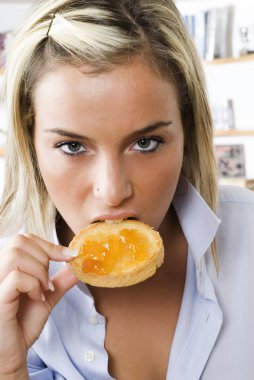 a sensul blond girl eating a toast with jam one morning during her breakfast clipart