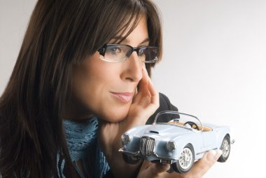 a young and elegant woman looking with interest at a model of a lancia car clipart