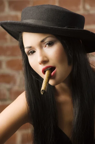 非常可爱的亚洲女孩戴着黑色帽子抽着雪茄 — 图库照片