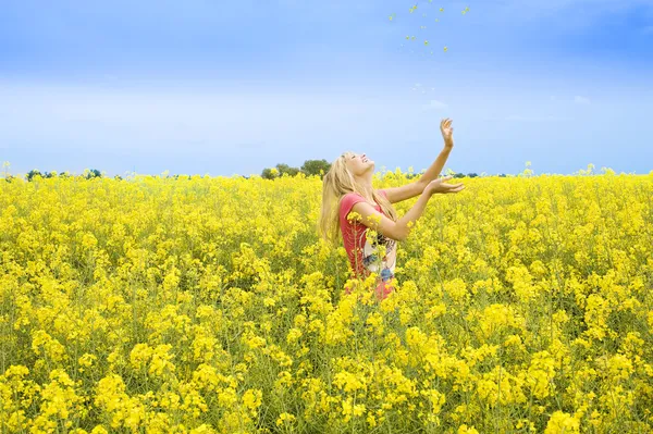 Glad tjej i en park med blommor — Stockfoto