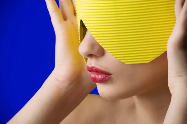 美丽的蓝色背景上的黄纸面具和红嘴唇的年轻女人肖像 — 图库照片