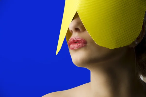 美丽的蓝色背景上的黄纸面具和红嘴唇的年轻女人肖像 — 图库照片