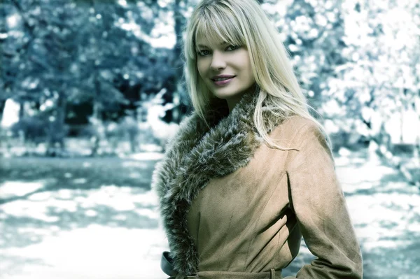 晴れた冬の日の公園で毛皮の冬のジャケットを持つ美しいブロンドの女の子のファッション撮影 — ストック写真