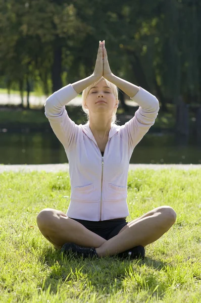 バックライトの公園の芝生の上ポーズ瞑想の若い女性 — ストック写真