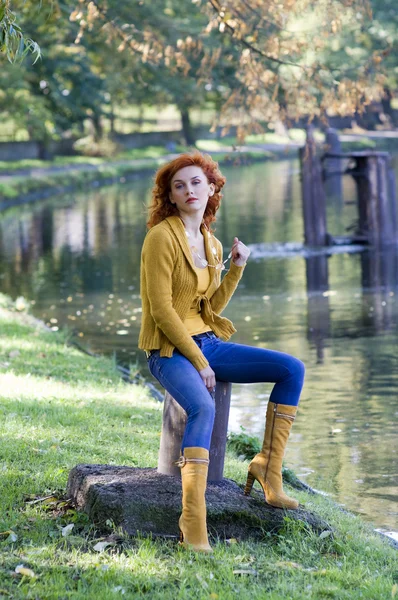 黄色のカジュアルな秋のドレスの川の近くに座っている美しい女性 — ストック写真