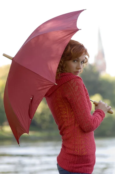 髪プルオーバーと赤い色の傘を持つかわいい女性の素敵な肖像画 — ストック写真
