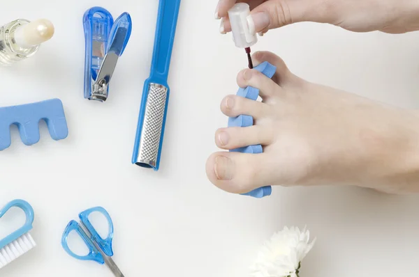 stock image putting red varnish on foot nails with acessory in background