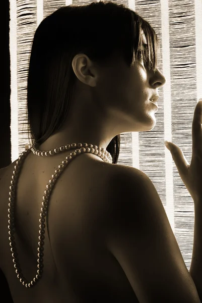 年轻和可爱的黑发女人裸肩玩珍珠的字符串 — 图库照片