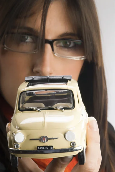 Eine junge Brünette mit Brille, die einen Fiat zeigt — Stockfoto