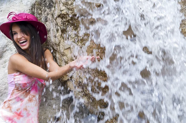 可爱的年轻女子 与粉红色的帽子和穿花的衬衫站在靠近瀑布 — 图库照片