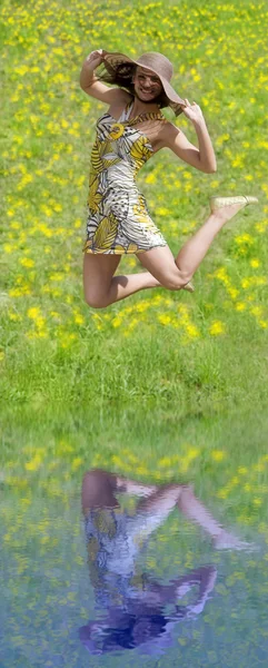 夏のドレスを彼女の麦わら帽子を維持ジャンプ運動若い女性 — ストック写真