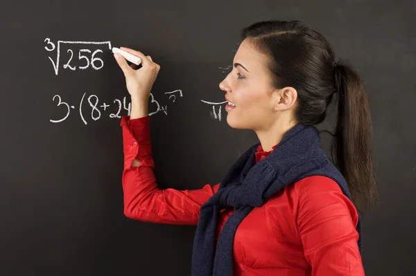 数学课上 一个年轻漂亮的大学生在黑板上写字 — 图库照片