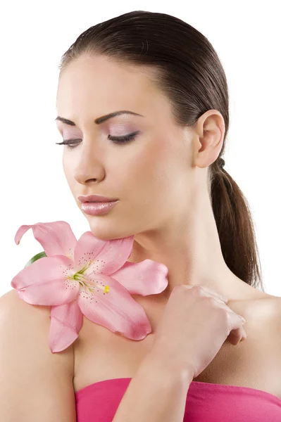 新鮮な彼女の肩にピンクのユリの花と白い背景の上の美しい女性の顔の肌の健康をオフします — ストック写真
