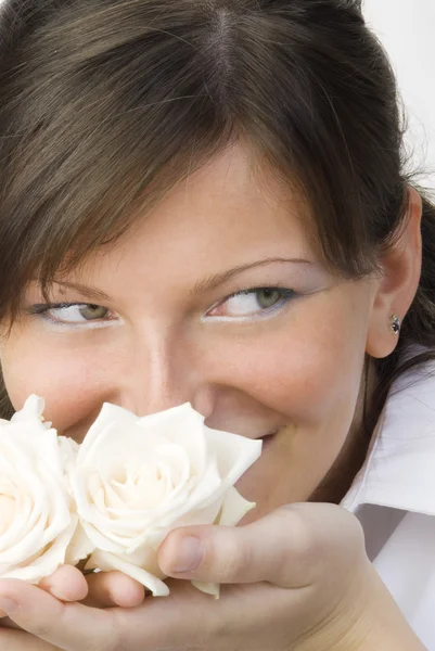 漂亮和年轻的女人在嗅到和她公平的眼睛微笑着她手中的玫瑰 — 图库照片