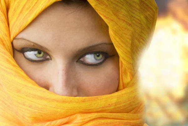 stock image attactive and strong eyes behind an orange scarf used like a burka