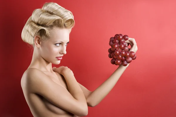 好拍摄的裸体金发美女在看红提葡萄的红色背景 — 图库照片
