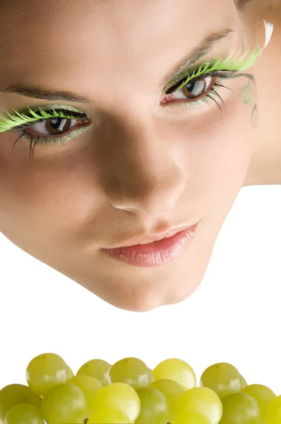 关闭一个可爱的女孩与人工睫毛和一些绿色的葡萄 — 图库照片