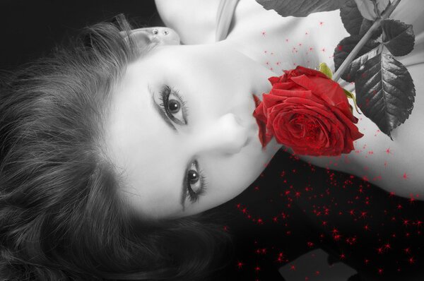 Portrait on black of a pretty brunette with a red rose