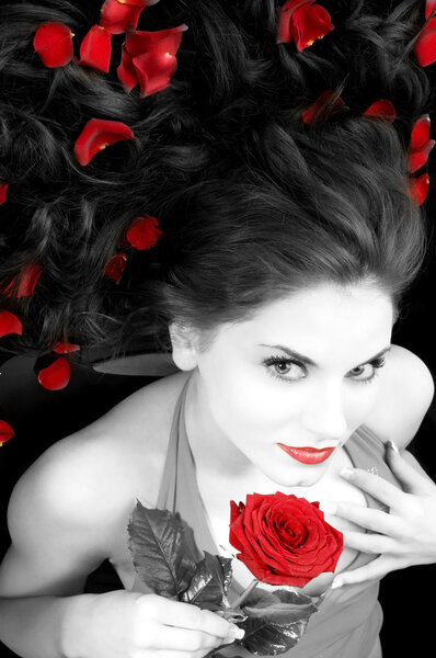 Wide angle portrait of pretty woman with red dress rose and petals