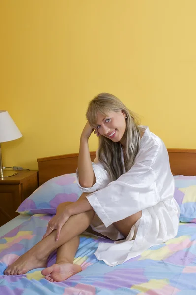 Sitting on the bed smiling — Stock Photo, Image