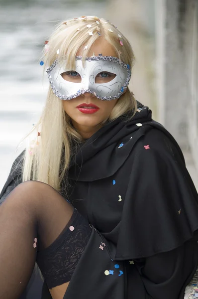 白いカーニバル マスクと黒マントと川の近くのブロンドの女の子 — ストック写真