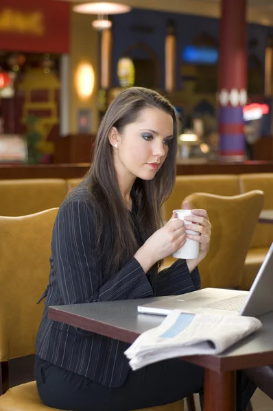 若いビジネス女性バーでノート パソコンを見ているとお茶を飲む — ストック写真