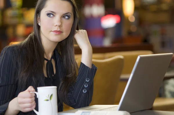 ノート パソコンとお茶を一杯とバーで座っていた美しい若い女性 — ストック写真