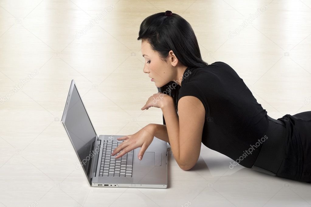beautiful young oriental woman using a laptop and laying down on the floor