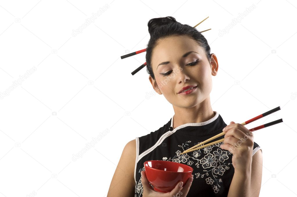 beautiful asian girl in japanes dress eating oriental food from a red cup using chopstick
