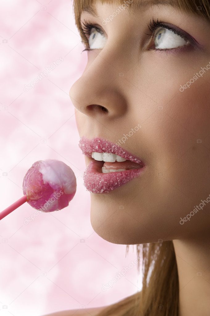 Pretty young girl with sugar on lips and a lollipop looking up