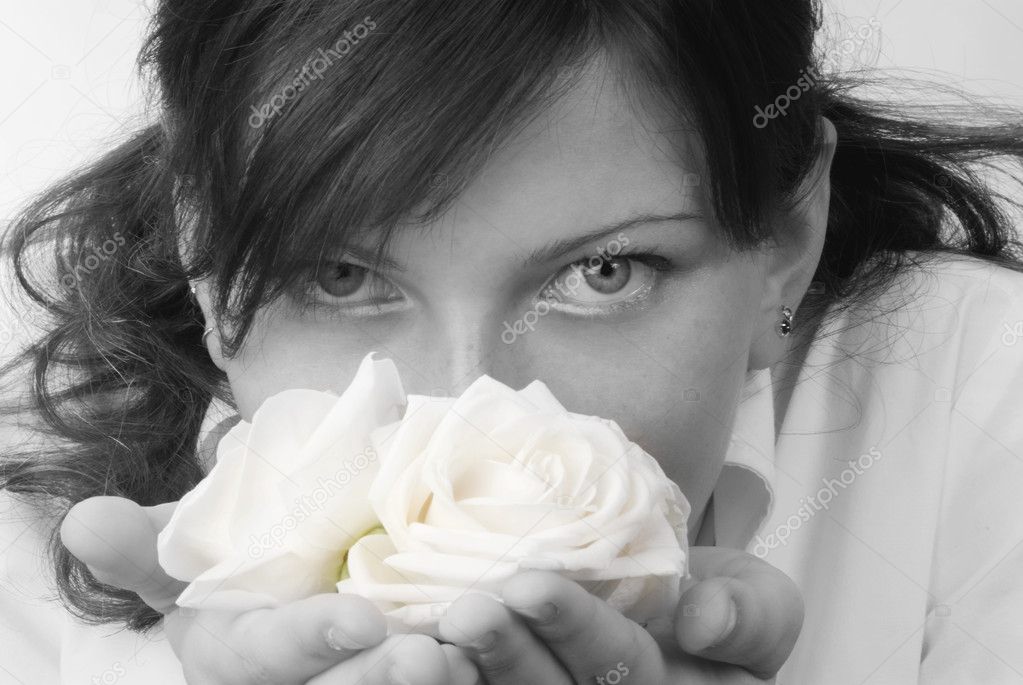 nice black and white portrait of a young woman with roses in her hands smelling and smiling with her fair eyes