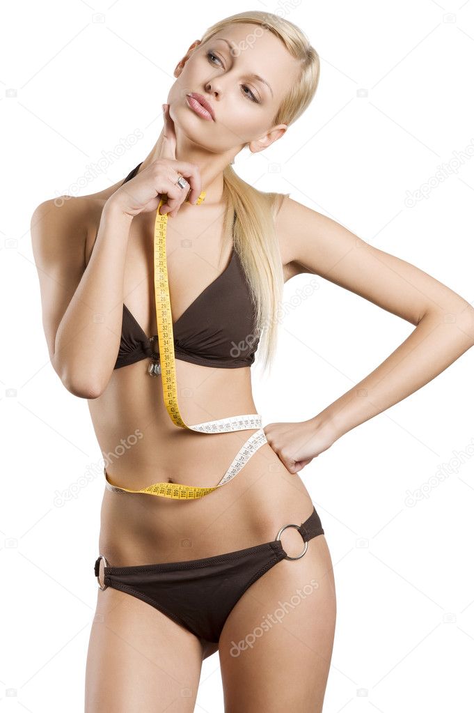 Young blond girl in bikini with a tape around her waistline in act to think about her fitness body
