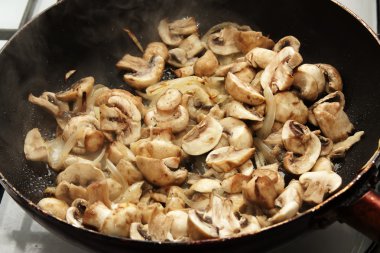 Fried mushrooms in oil in a frying pan clipart