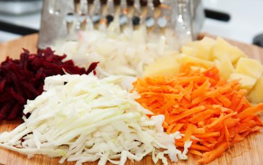 Grated raw vegetables on a wooden board clipart