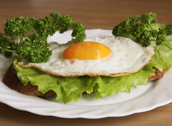 Sanduíche Com Ovo Frito Uma Placa Branca Uma Superfície Madeira — Fotografia de Stock
