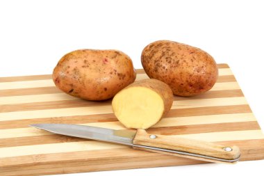 Çiğ patates yumrular bir kesme tahtası üzerinde yalan