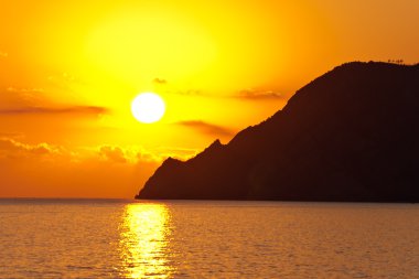 Big sun setting down over the sea and mountains clipart