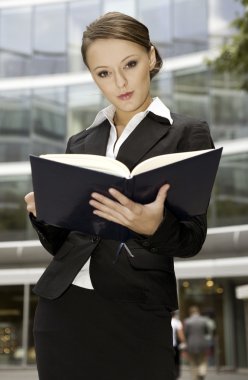 Young brunette businesswoman outdoors with a notebook clipart