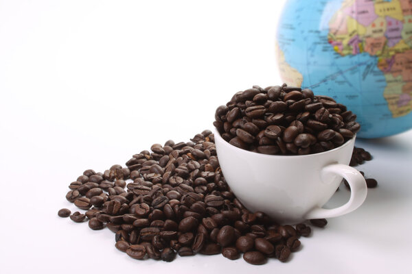 Roasted coffee beans and a coffee cup and a globe
