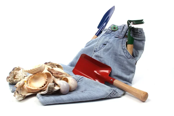 Childrens toy garden tools and a blue jeans on the beach — Stock Photo, Image