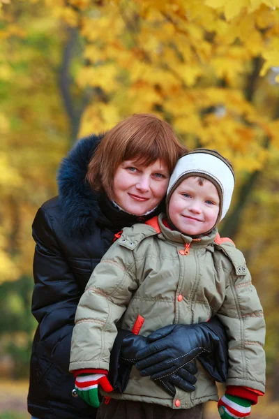 黄金の秋の都市公園で小さな息子を持つ母 — ストック写真
