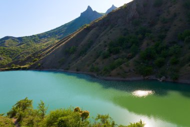 Akşam güneşi yansıma güzel göl ve yaz kayalara dağ ardında (zelenogorye Köyü, Kırım, Ukrayna)