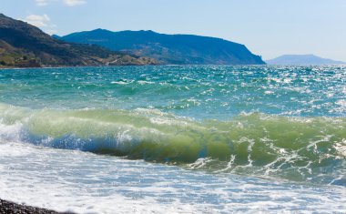 Sea surf wave break on coastline and Meganom cape on horizon right (Crimea, Ukraine) clipart