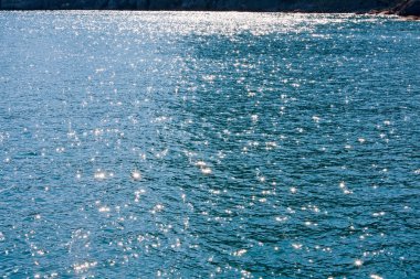 Azure sea water surface with ripple and sun reflection sparkles clipart