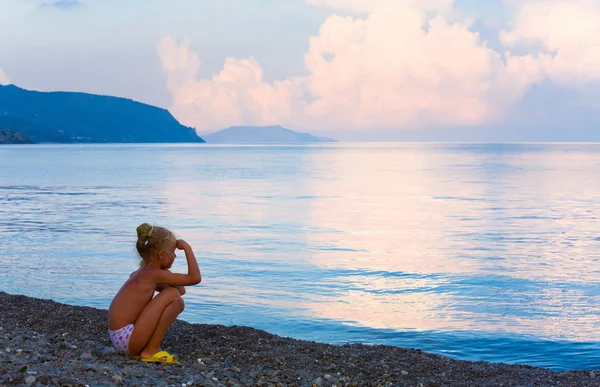 Solnedgång, glänsande havet ytbehandlar och flicka på stranden — Stockfoto